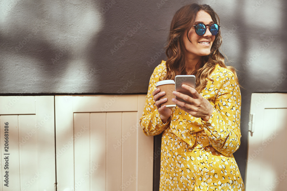 Woman drinking coffee while reading text massages in the city