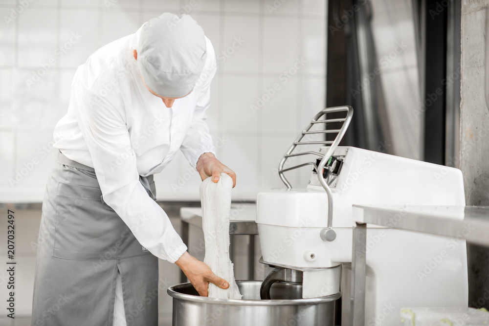 Man mixing dough with professional kneader machine at the manufacturing