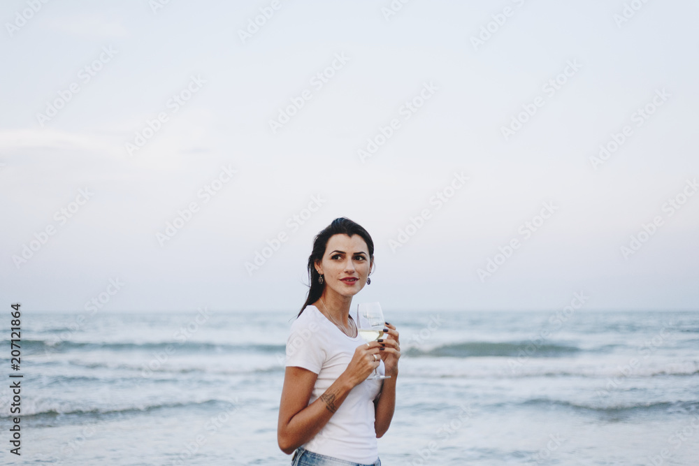 一个女人在海滩边喝着一杯葡萄酒