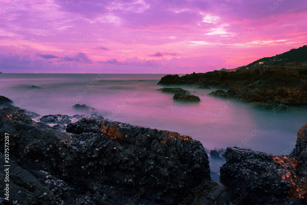 Long exposure image of Dramatic sky seascape with rock in sunset scenery background.