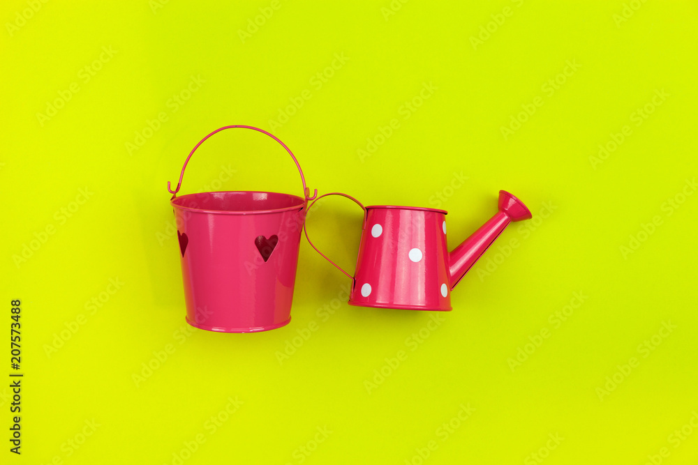 Pink watering can isolated on a yellow background.