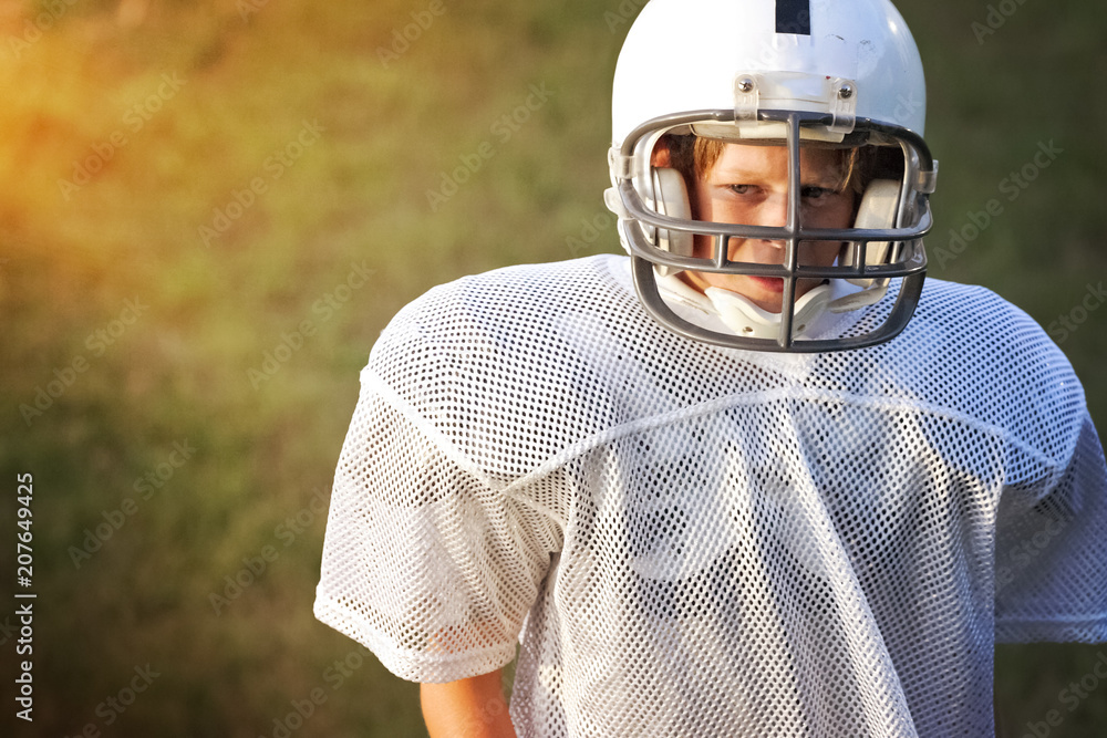 Young boy in a football uniform looking sad