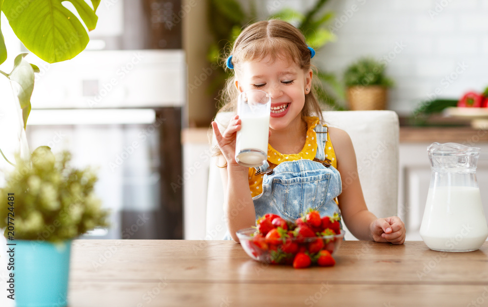 happy baby girl eating strawberries with milk