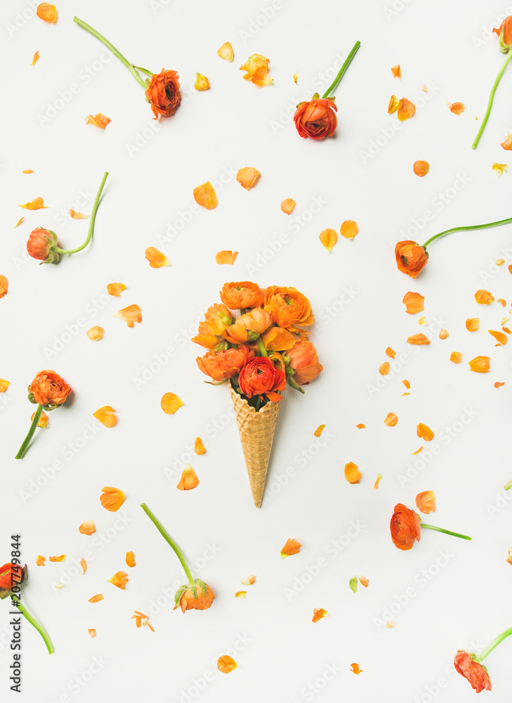 Flat-lay of waffle sweet cone with orange buttercup flowers over white background, top view, vertica