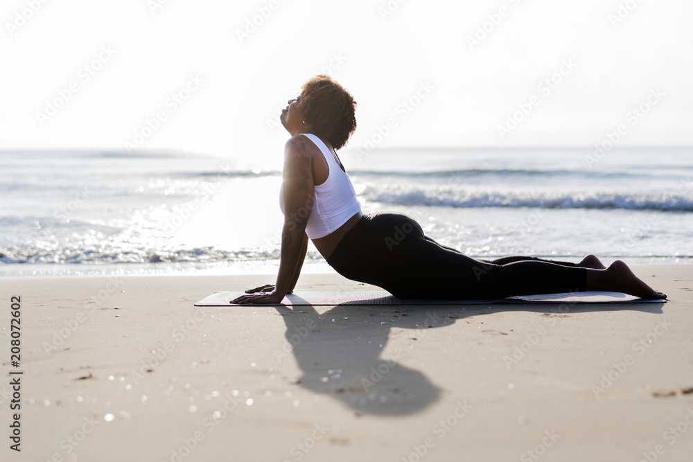 African American woman practicing yoga at the beach