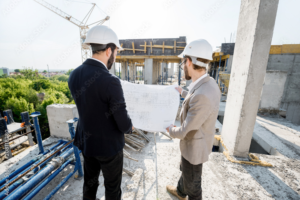 两名工程师或建筑师在施工期间一起绘制房屋图纸