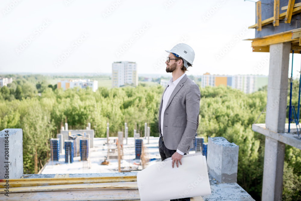 站在室外结构图纸上监督房屋施工过程的男子