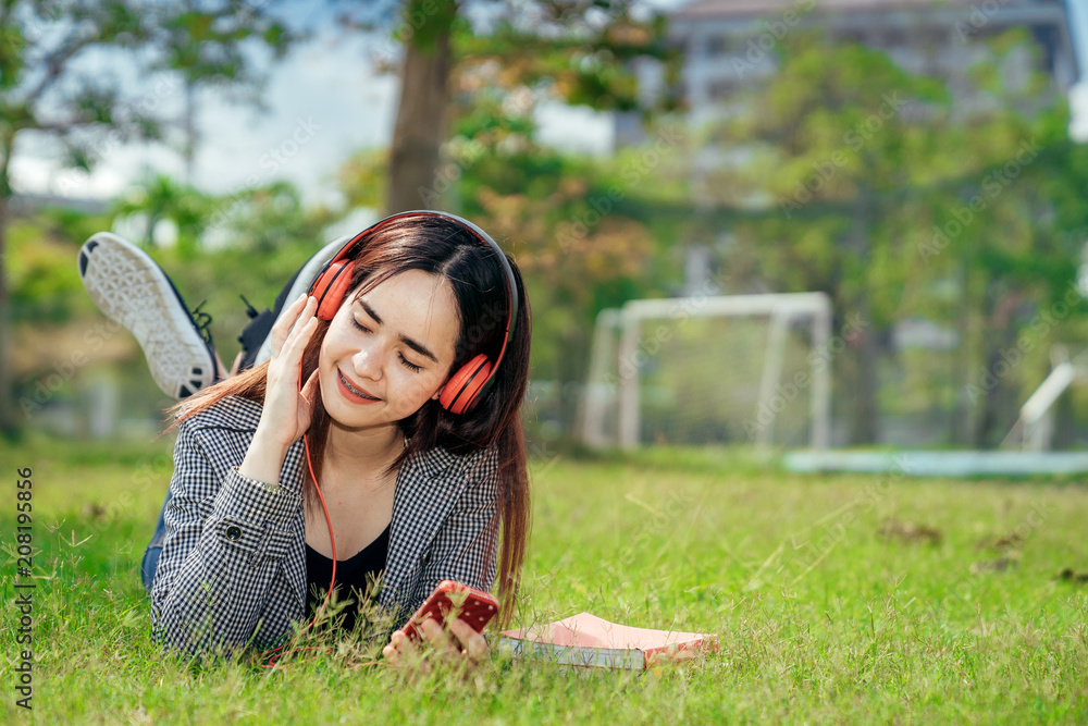 一个年轻的十几岁的大学生在暑假里微笑着看书。她在听