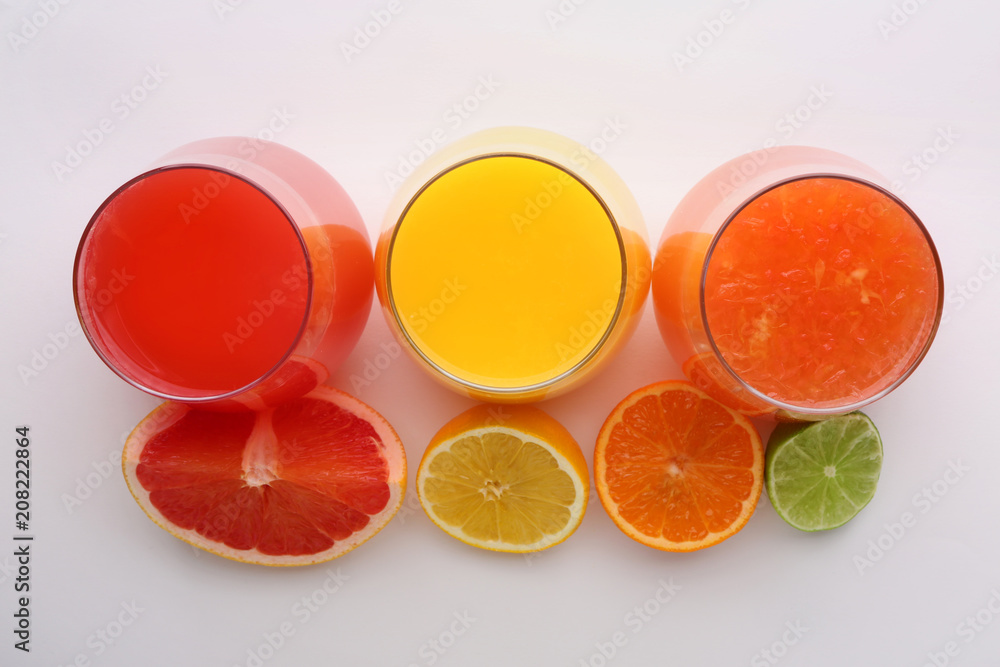 Glasses with delicious citrus juice and fresh fruits on white background