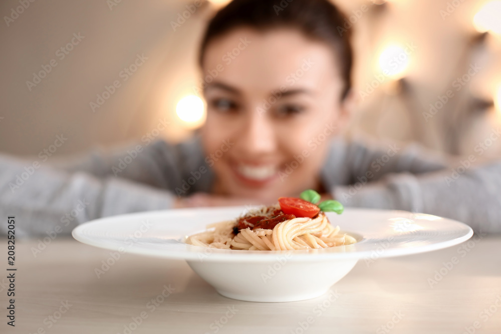 Plate with tasty pasta and blurred woman on background