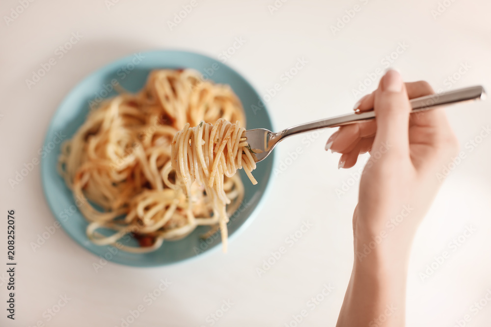 年轻女人在餐桌上吃美味的意大利面，特写