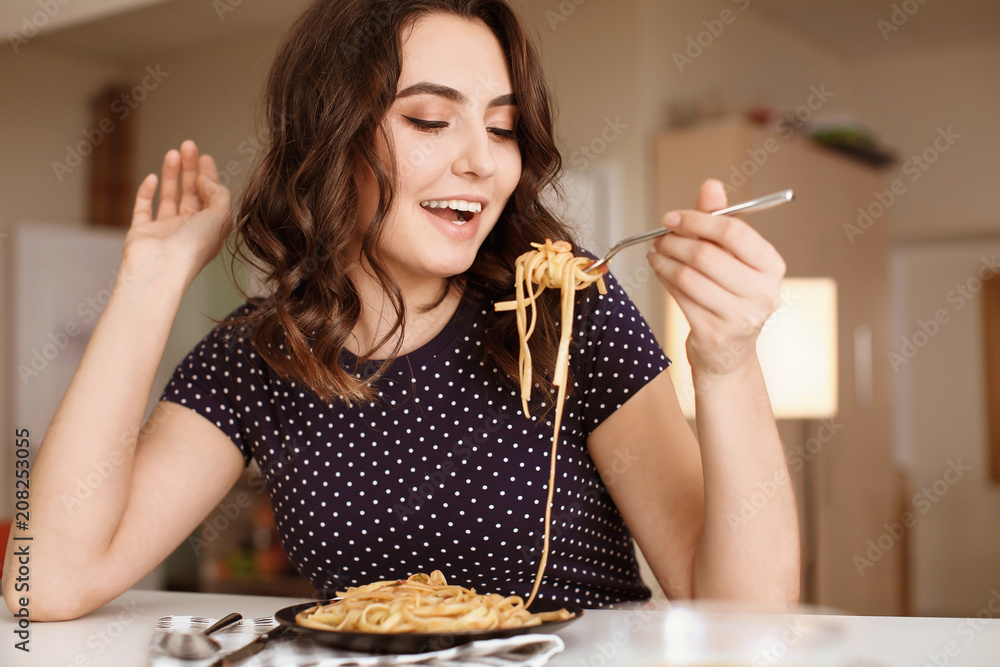 年轻女人在餐桌上吃美味的意大利面