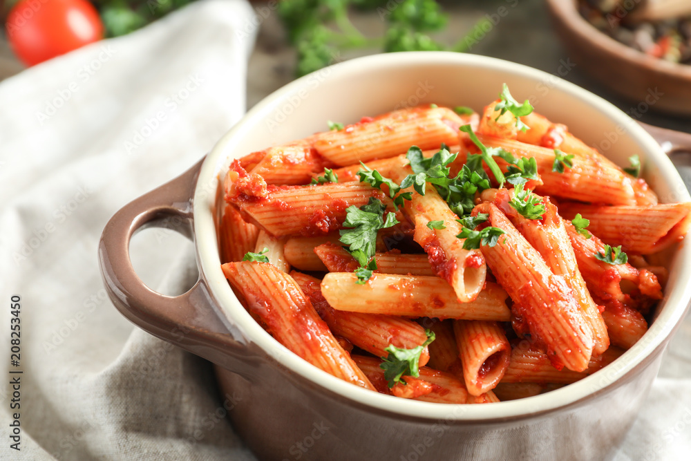 Casserole of tasty penne pasta with tomato sauce on table, closeup