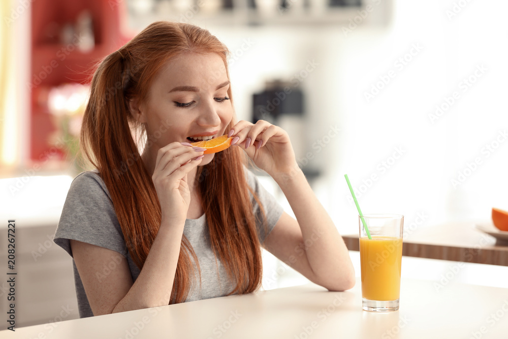 漂亮的年轻女人在厨房吃柑橘类水果