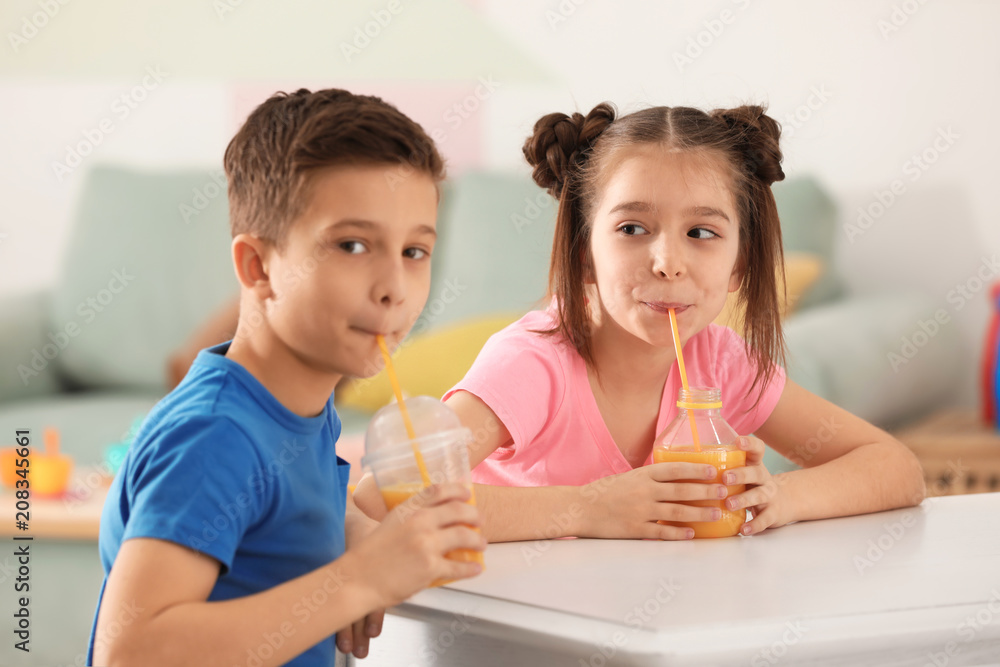 Funny little children drinking citrus juice at home