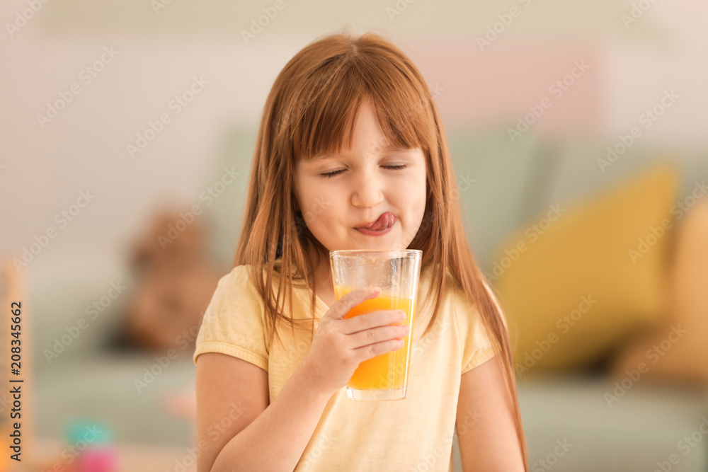 Funny little girl drinking citrus juice at home