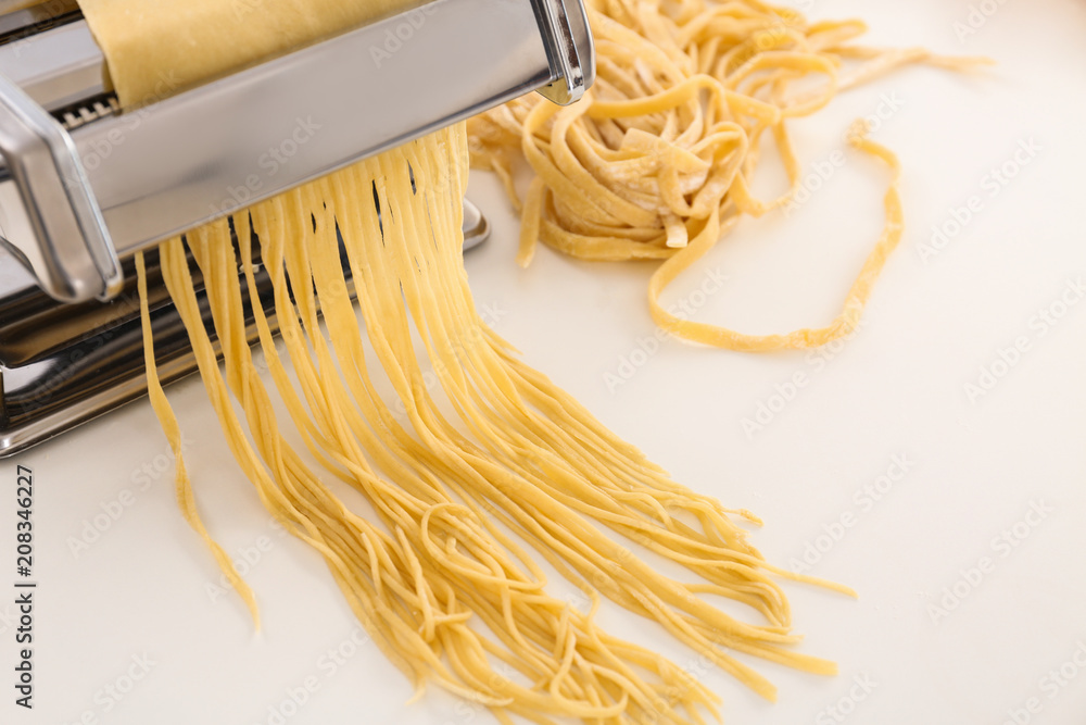 Metal pasta maker with dough on white background