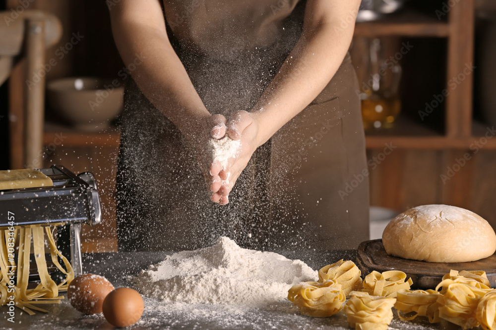 女人在桌子上撒面粉。意大利面食谱