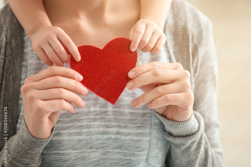 Mother and her little daughter holding red heart, closeup