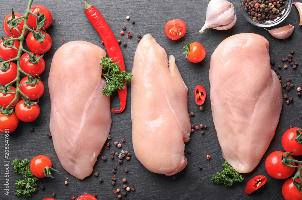 Composition with raw chicken fillet, vegetables and spices on slate plate, flat lay