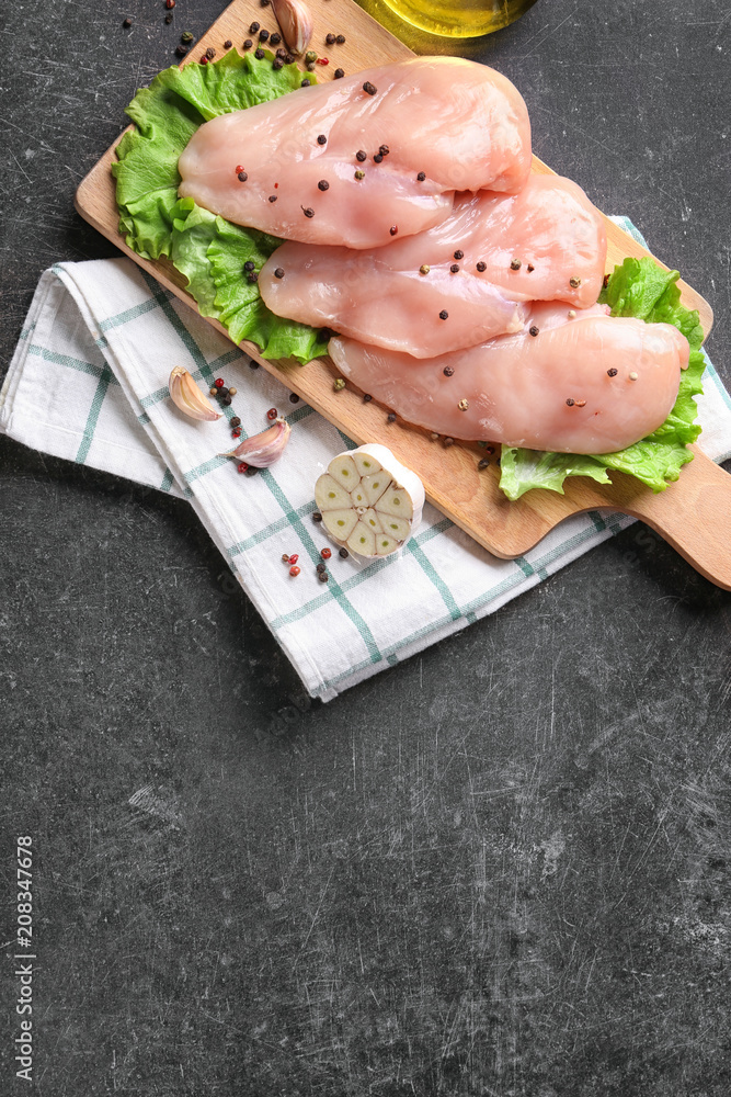 Composition with raw chicken fillet on dark background