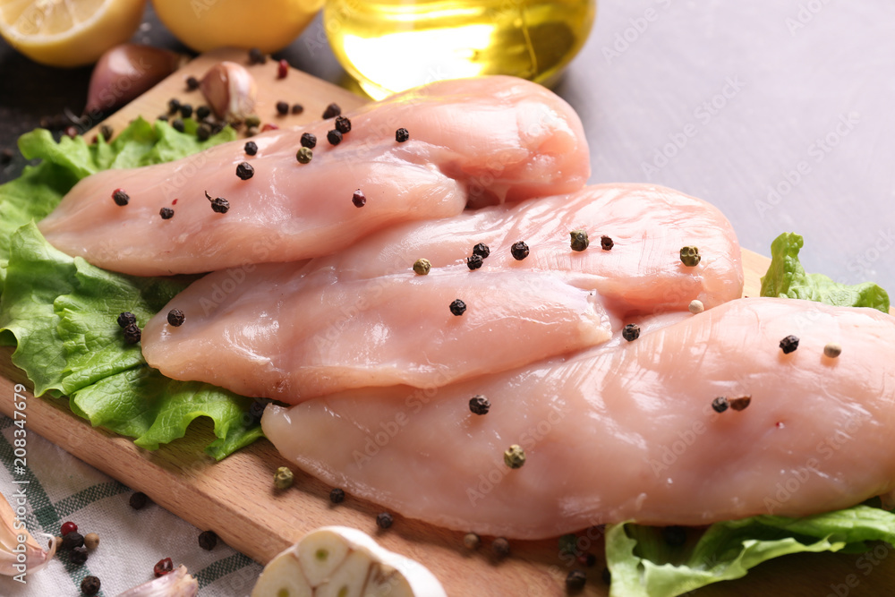 Raw chicken fillet with spices on wooden board, closeup