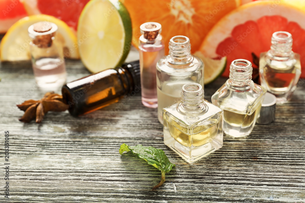 Bottles with essential oils and citrus fruits on wooden background