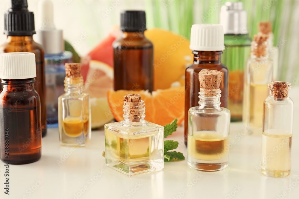 Bottles with citrus essential oils on white table