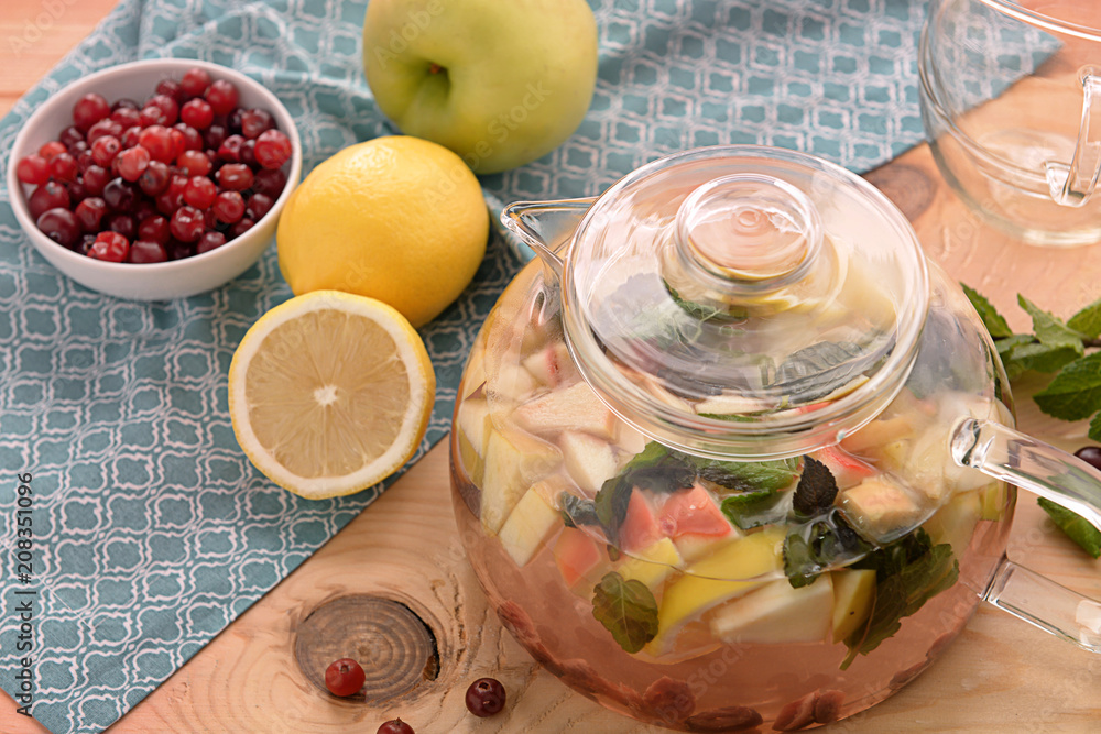 Teapot with aromatic fruit tea on table