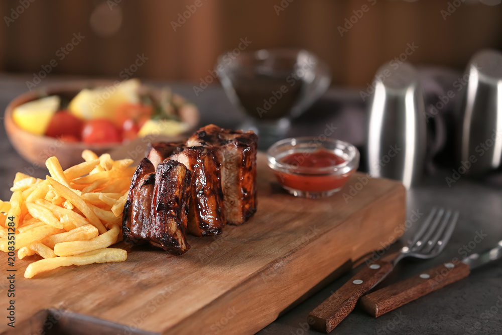 Delicious grilled ribs and french fries on wooden board