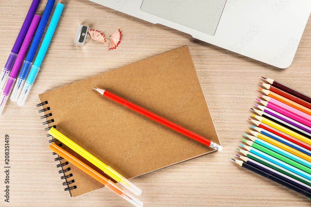 Workplace composition with laptop, notebook and color pencils on table, flat lay