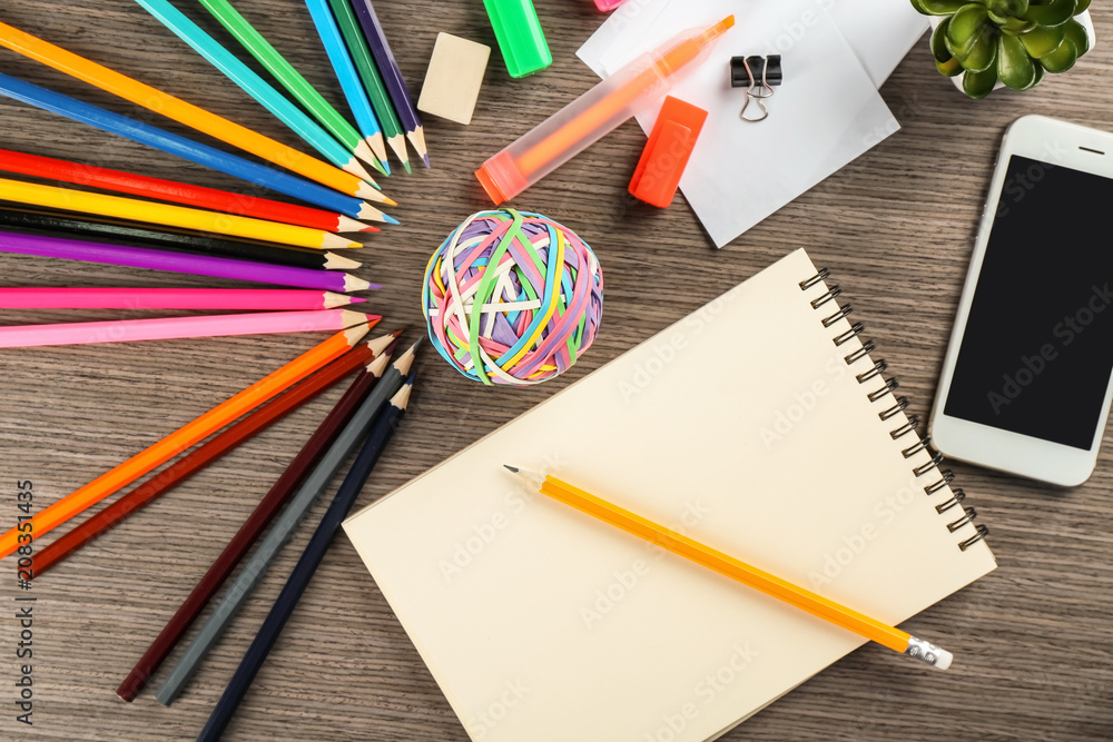 Workplace composition with smartphone, notebook and color pencils on table, flat lay