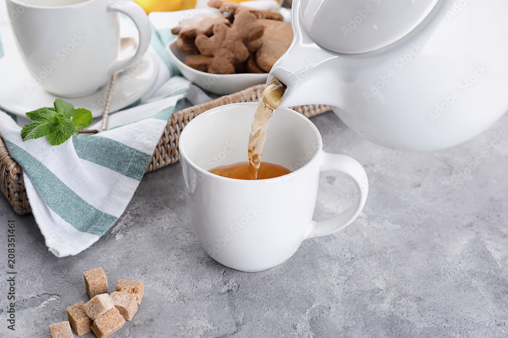 把热茶倒进桌子上的杯子里