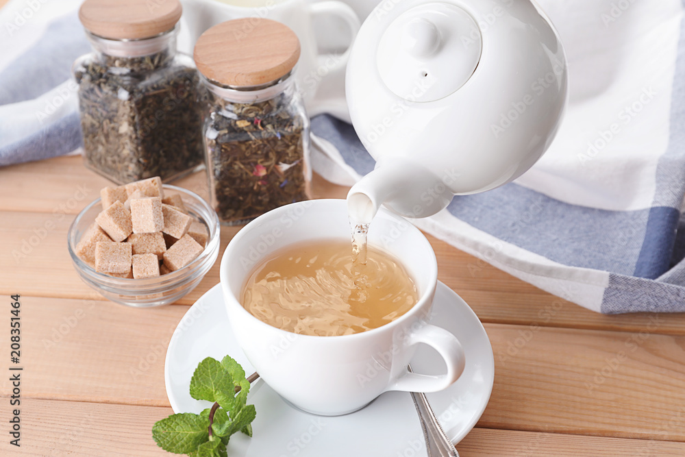 Pouring hot tea into cup on table