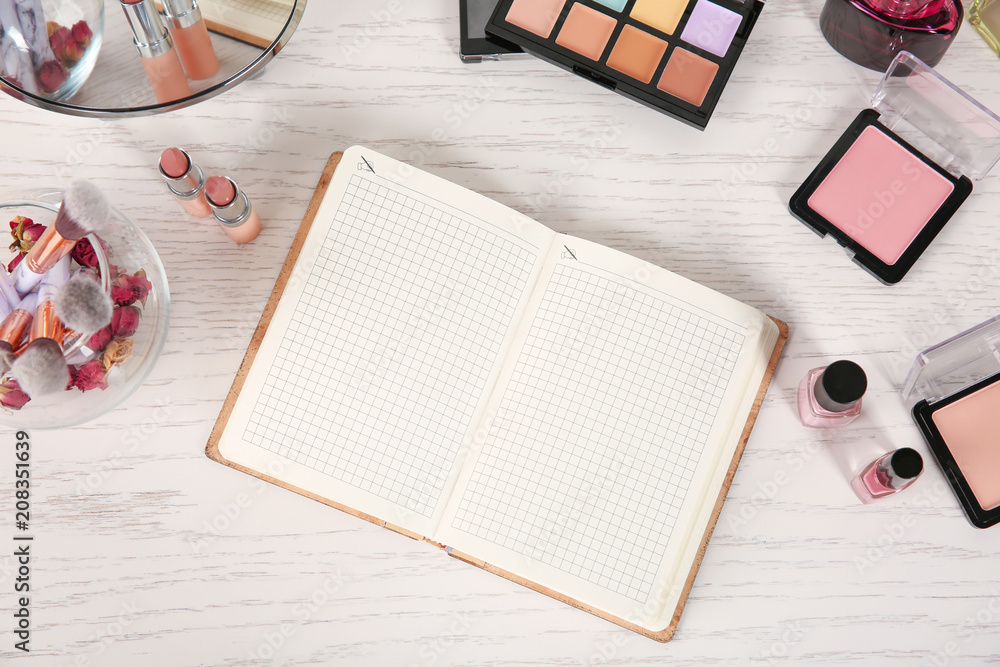 Flat lay composition with notebook and professional cosmetics on wooden background