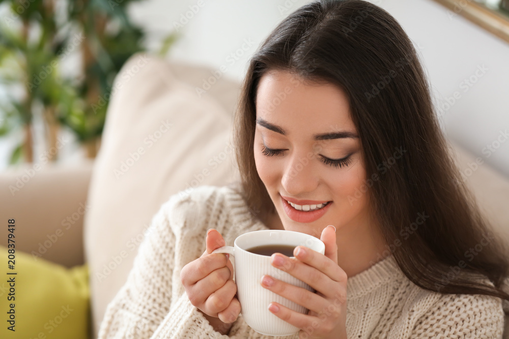 家里有一杯热茶的漂亮年轻女人