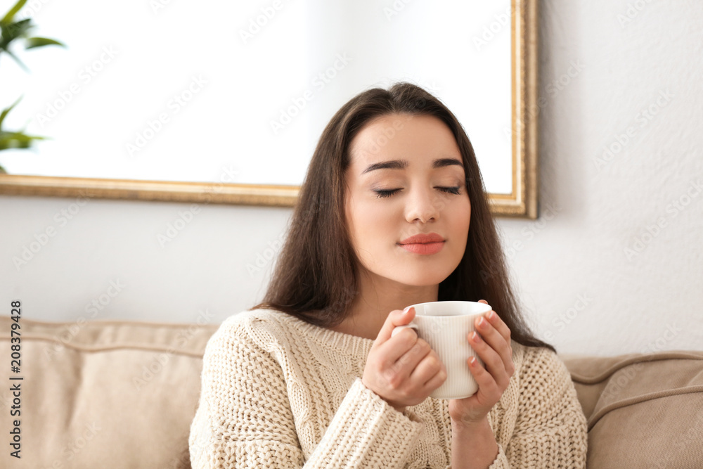 家里有一杯热茶的漂亮年轻女人