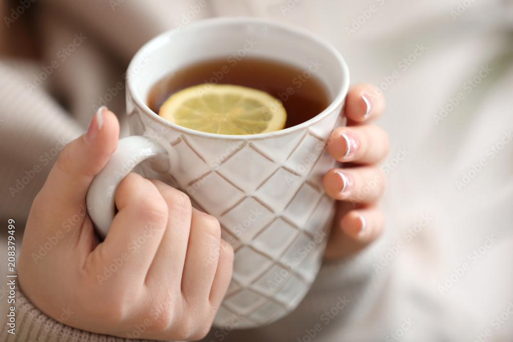 Beautiful young woman with cup of hot tea, closeup