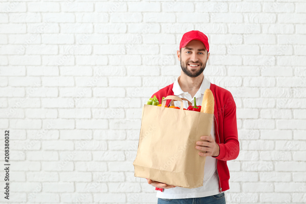 外卖员拿着砖墙背景上的食品纸袋