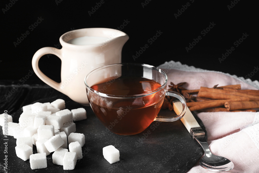 Composition with aromatic tea and milk on table against dark  background