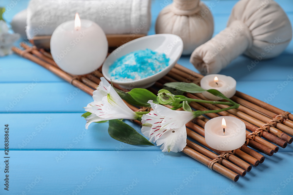 Beautiful spa composition with sea salt, flowers and candles on wooden table