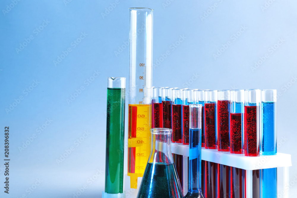 Chemical glassware with different liquids on color background