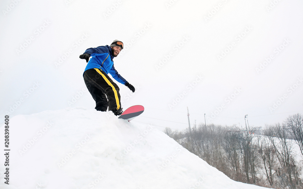 冬季度假区斜坡上的男单板滑雪运动员