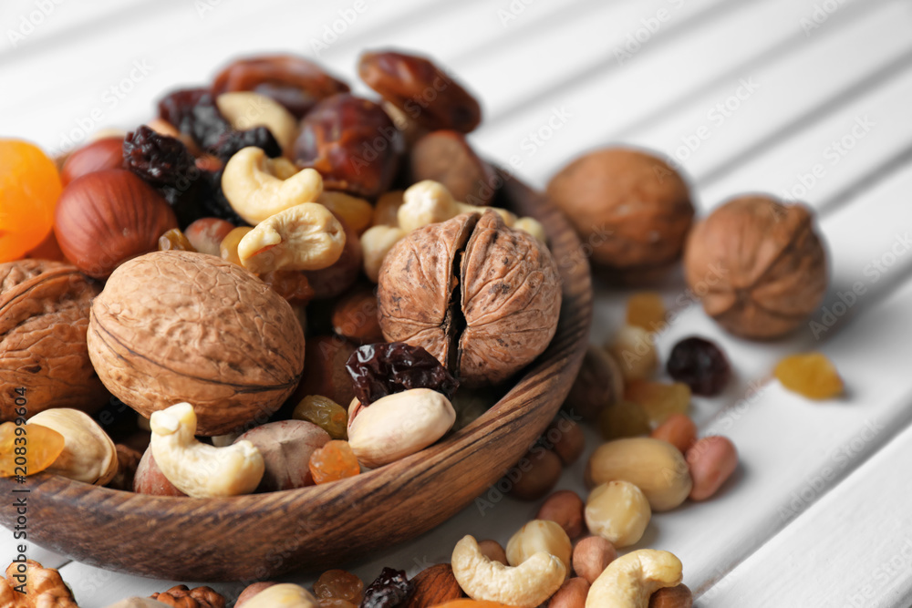 Plate with different nuts and dried fruits on table, closeup