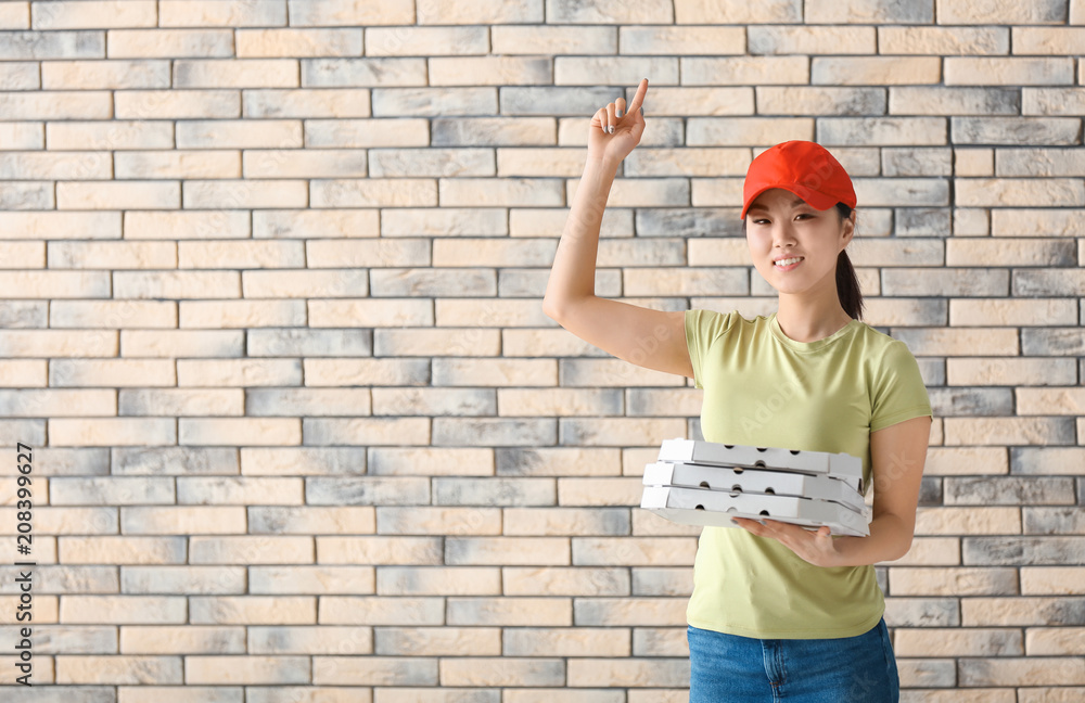 Asian woman with cardboard pizza boxes on brick wall background. Food delivery service