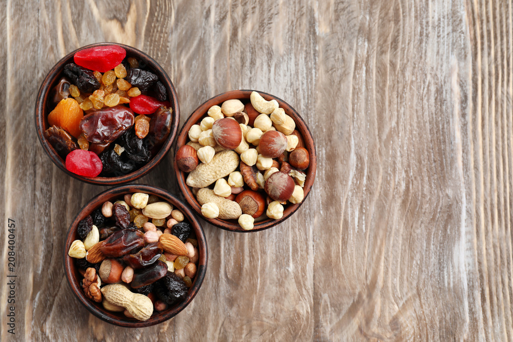 Bowls with mix of dried fruits, berries and nuts on wooden background, top view