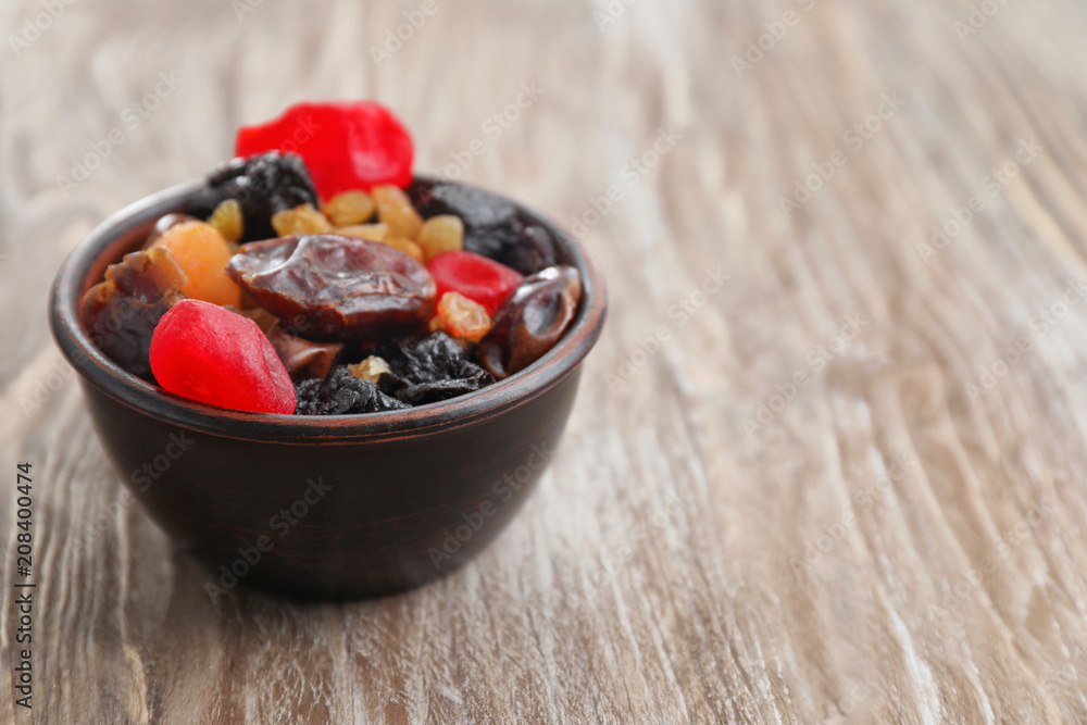 Bowl with mix of dried fruits and berries on wooden background