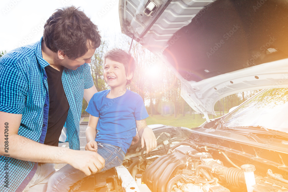 Happy father and son repairing car outside