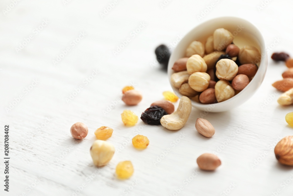 Bowl with various tasty nuts on wooden table