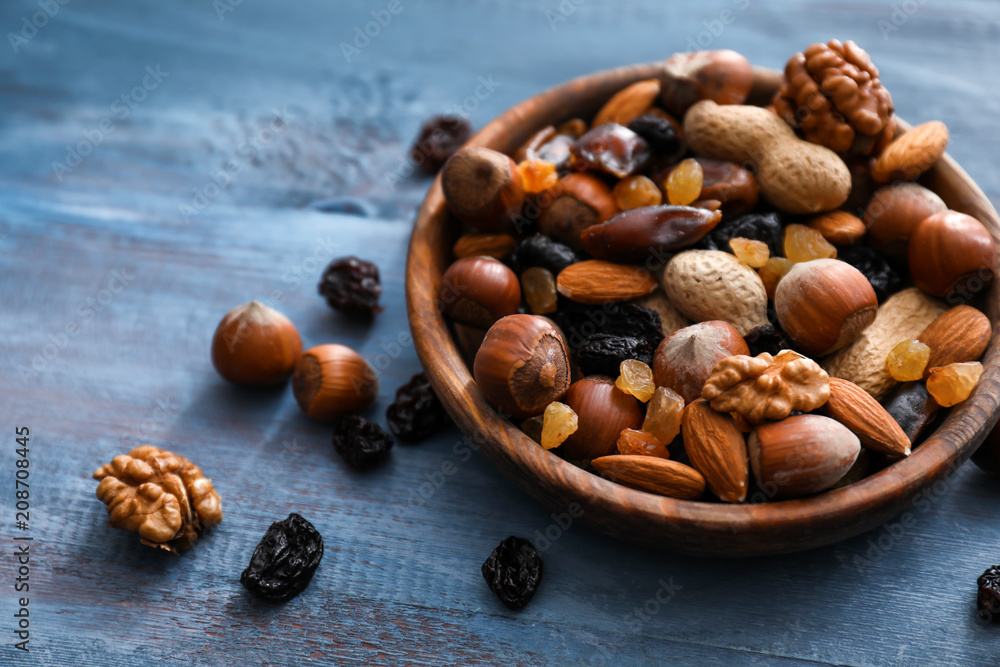 Bowl with various tasty nuts and dried fruits on wooden table